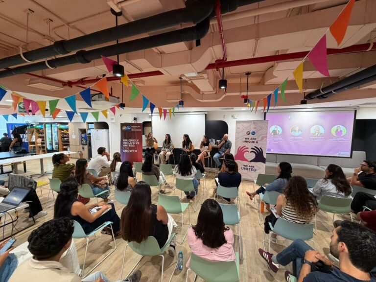 Panel de líderes conversando sobre diversidad, equidad e inclusión frente a colaboradores en un espacio corporativo en Perú